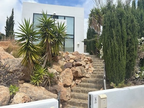 A modern building with a stone staircase, surrounded by various plants and trees. - The Black Natural Park Cabo de Gata-Nijar (Las Negras Nijar Almeria)