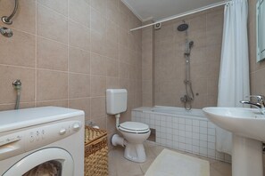 Un baño con lavadora, inodoro, bañera y lavabo.