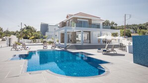 A modern house with a swimming pool, outdoor furniture, and a view of the surrounding landscape.