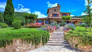 A stone house with a stone staircase leading to the entrance, surrounded by lush greenery and flowering plants. - Villa Bella 8, Emma Villas (Massa Martana)