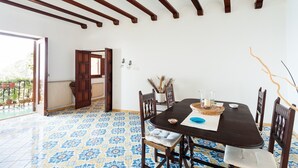 A dining area with a dark wooden table, blue patterned floor tiles, and a view of the outside balcony. - Casa Annalu with sea view - My Rental Homes (Positano)