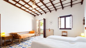 A bedroom with a bed, a wooden bench, a table, and a chair. There is a window with shutters and a radiator on the wall. - Casa Annalu with sea view - My Rental Homes (Positano)