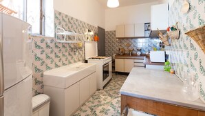 A compact kitchen with patterned tiles, a stove, a sink, and a refrigerator. - Casa Annalu with sea view - My Rental Homes (Positano)