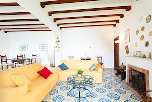 A living room with a yellow sofa, a round coffee table, and a fireplace.