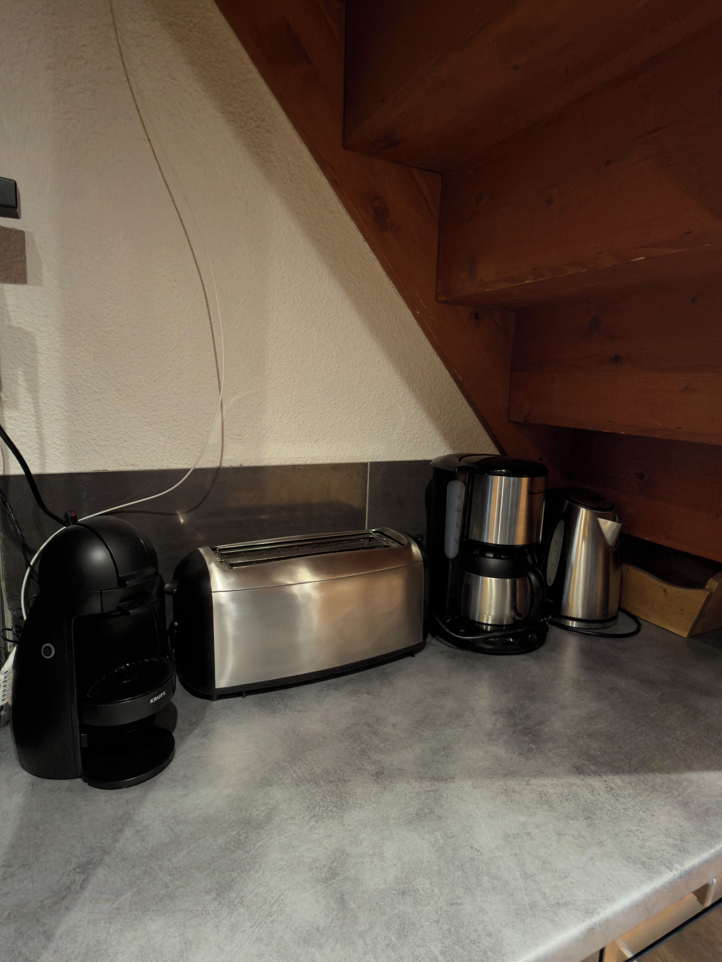 Un plan de travail de cuisine avec un grille-pain, une machine à café et une bouilloire.