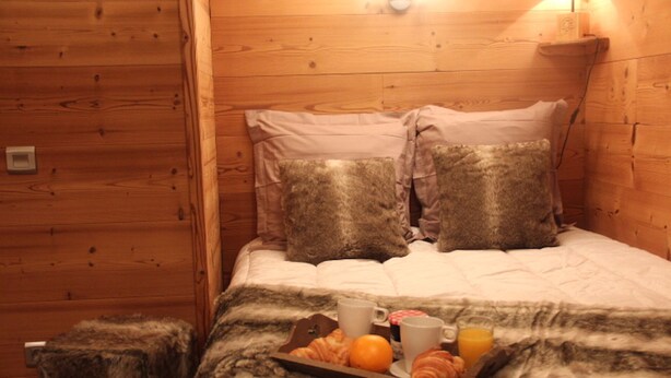 A cozy wooden room with a bed, two pillows, a tray with croissants, an orange, a glass of orange juice, and a cup. - Apartment/ flat - VAL THORENS (Les Belleville)