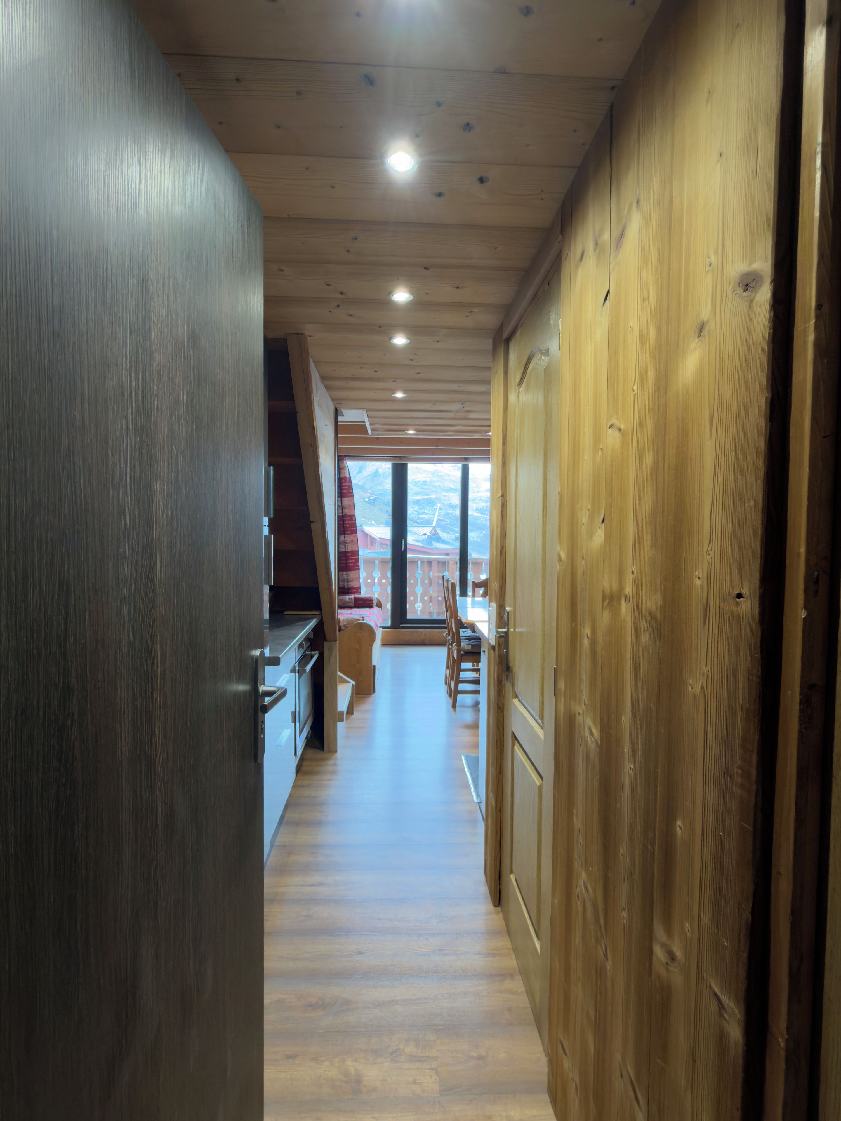 Un couloir intérieur en bois donnant sur un balcon.