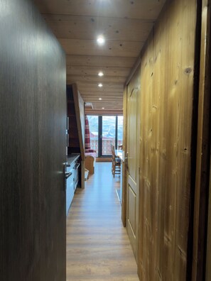 Un couloir intérieur en bois donnant sur un balcon.