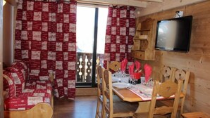 A cozy room with a wooden interior, a dining table set for two, and a television mounted on the wall. - Apartment/ flat - VAL THORENS (Les Belleville)