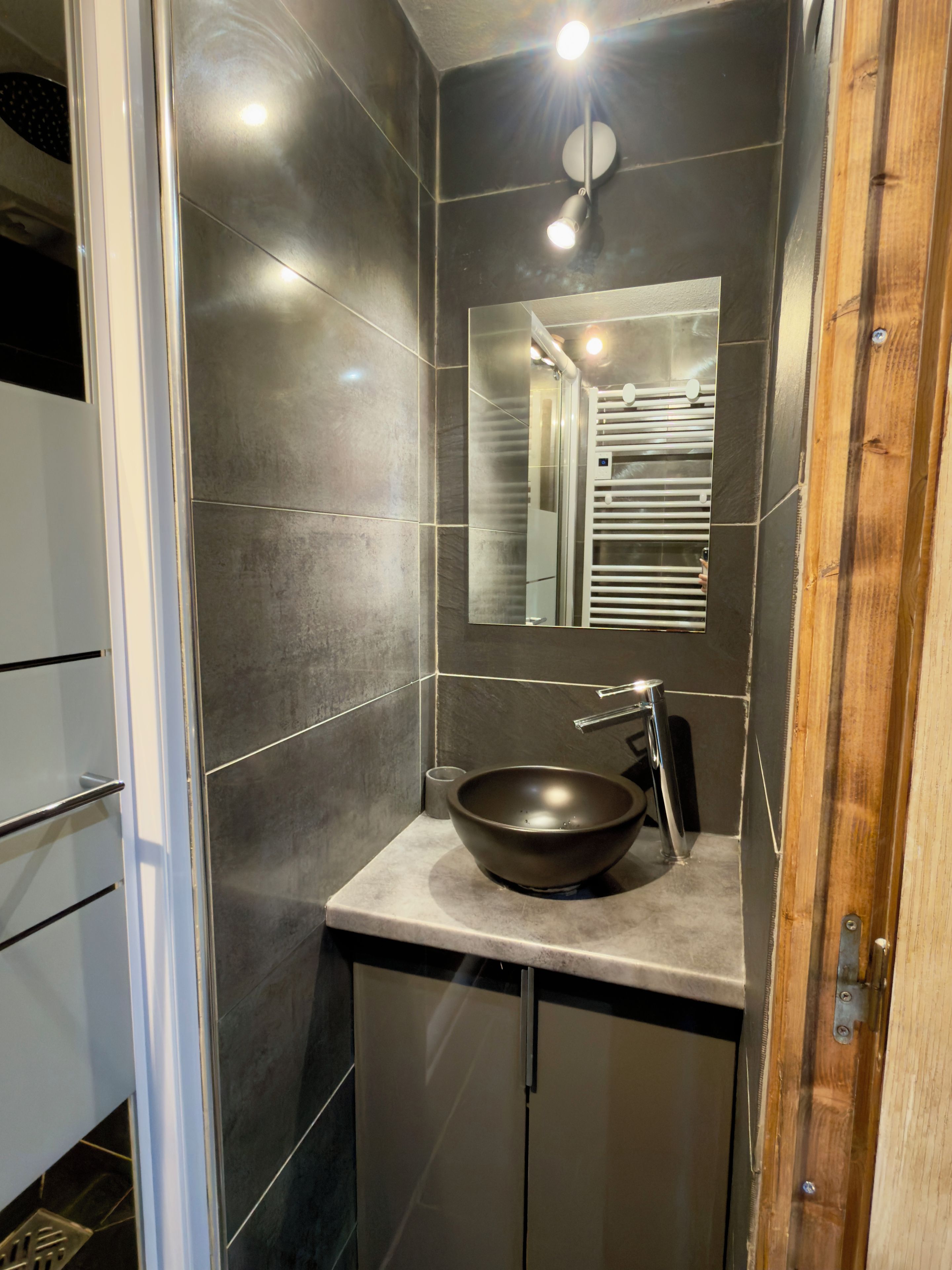 A bathroom with a modern design, featuring a large mirror, a vessel sink, and a towel rack.