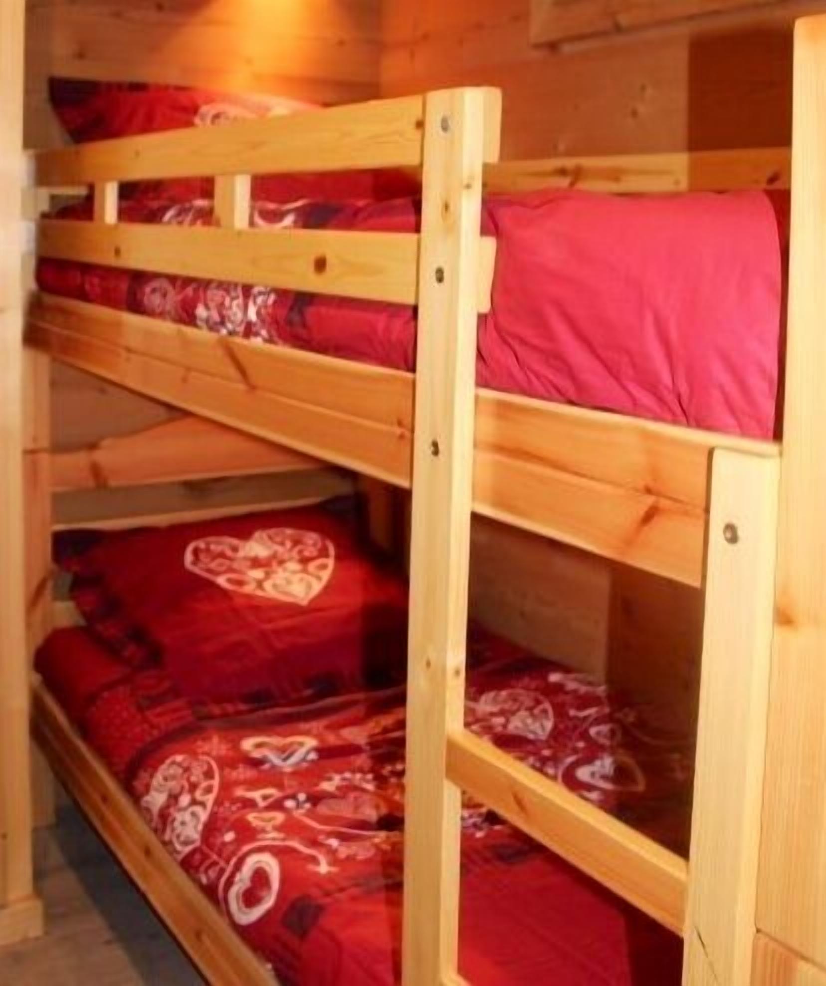 A bunk bed with red bedding and a wooden frame.