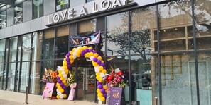 A storefront with a large arch of balloons and floral arrangements.