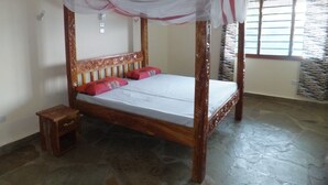 A four-poster bed with a canopy, a small wooden nightstand, and a window with patterned curtains. - Villa with pool, stunning sea views, with own chef and staff on request (Msambweni)