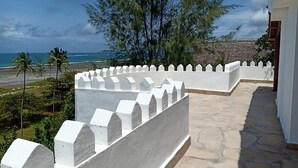 A white-walled balcony with a stone floor, overlooking a beach and palm trees. - Villa with pool, stunning sea views, with own chef and staff on request (Msambweni)