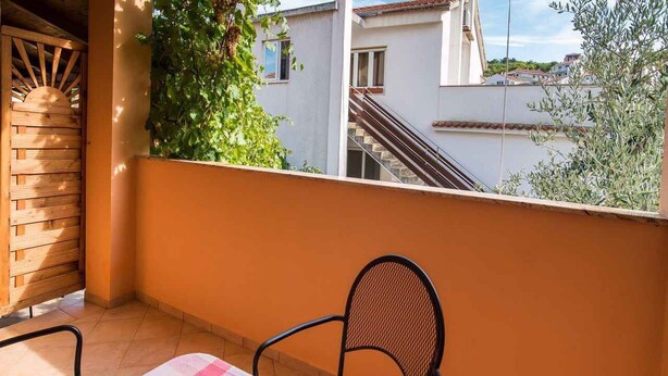A balcony with a table set for two, a bowl of fruit, and a view of buildings in the background. - Studio with internet access, near the sea (Vrbnik)