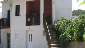 A two-story building with a white facade, a red-tiled roof, and a staircase leading to the upper floor. There is a small balcony with potted plants on the ground floor. - Studio with internet access, near the sea (Vrbnik)