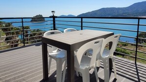 A terrace with a table and chairs overlooking a body of water and distant hills. - A day in Geoje Pension (Geoje)