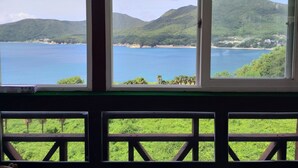 A view from a window overlooking a coastal landscape with mountains and a body of water. - A day in Geoje Pension (Geoje)