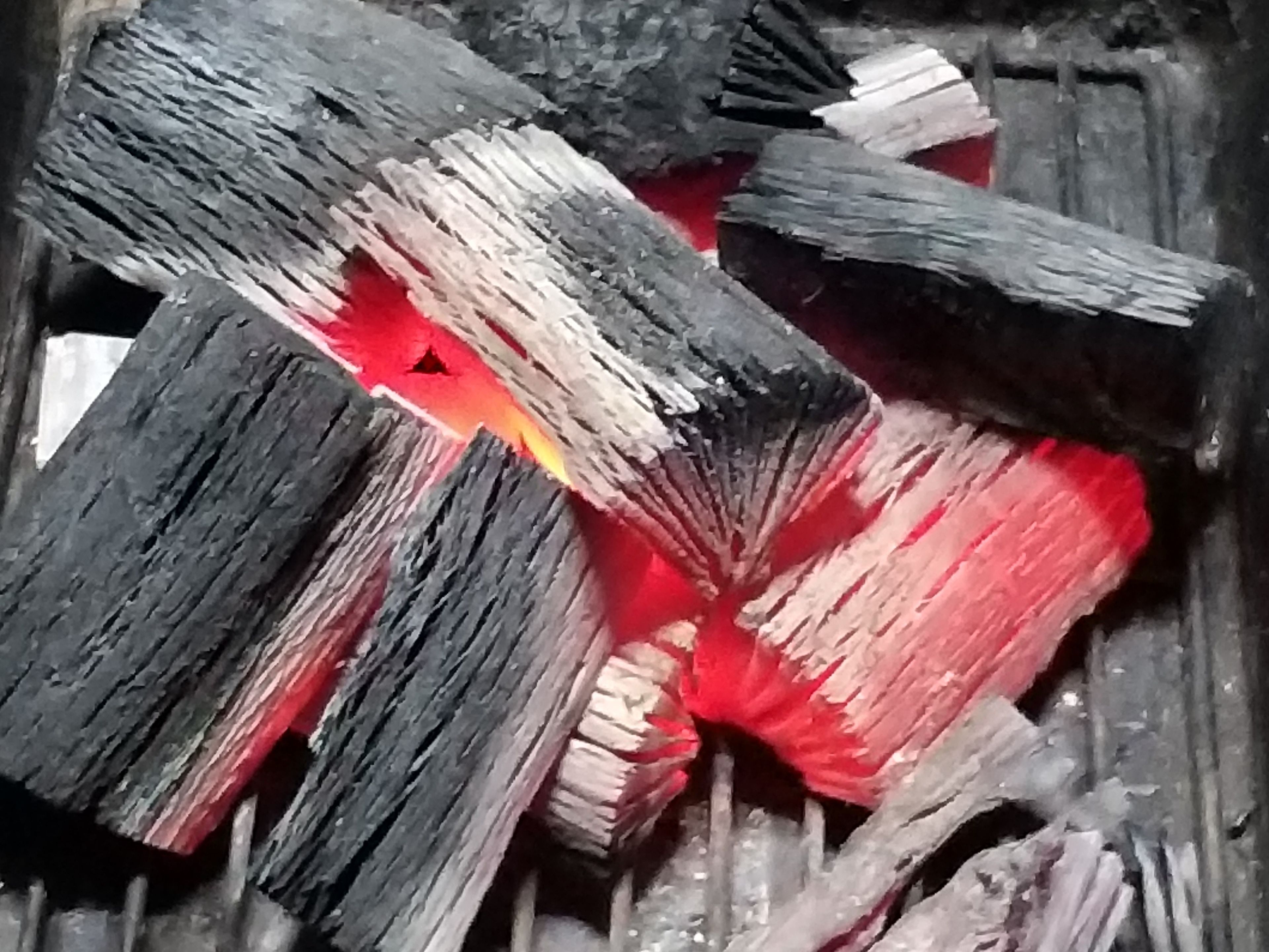 A close-up of burning charcoal with glowing embers.