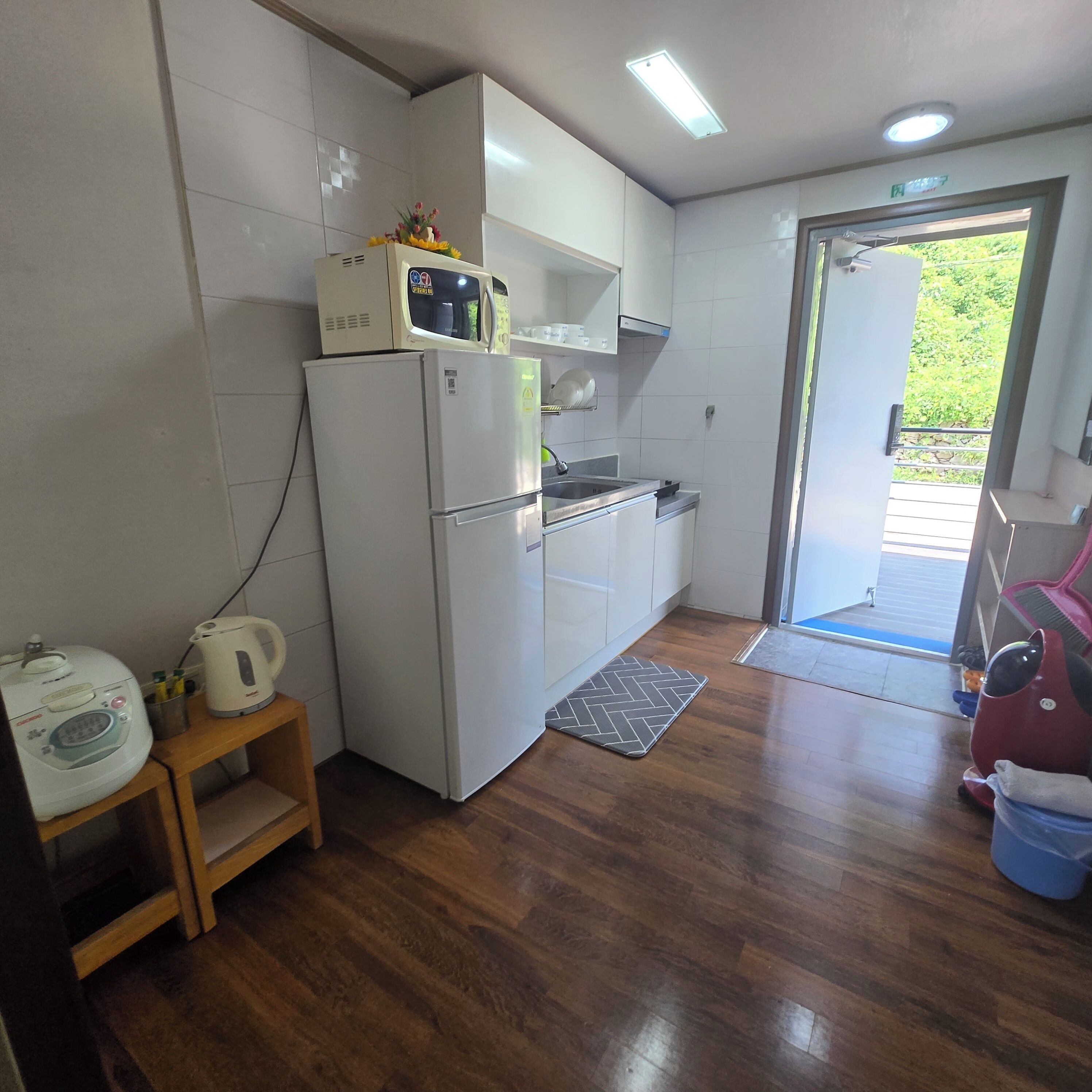 Cocina compacta con refrigerador, microondas y lavamanos.
