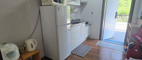 Cocina compacta con refrigerador, microondas y lavamanos.
