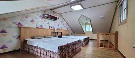 A bedroom with two beds, wooden flooring, a sloped ceiling, and a geometric-patterned wall.