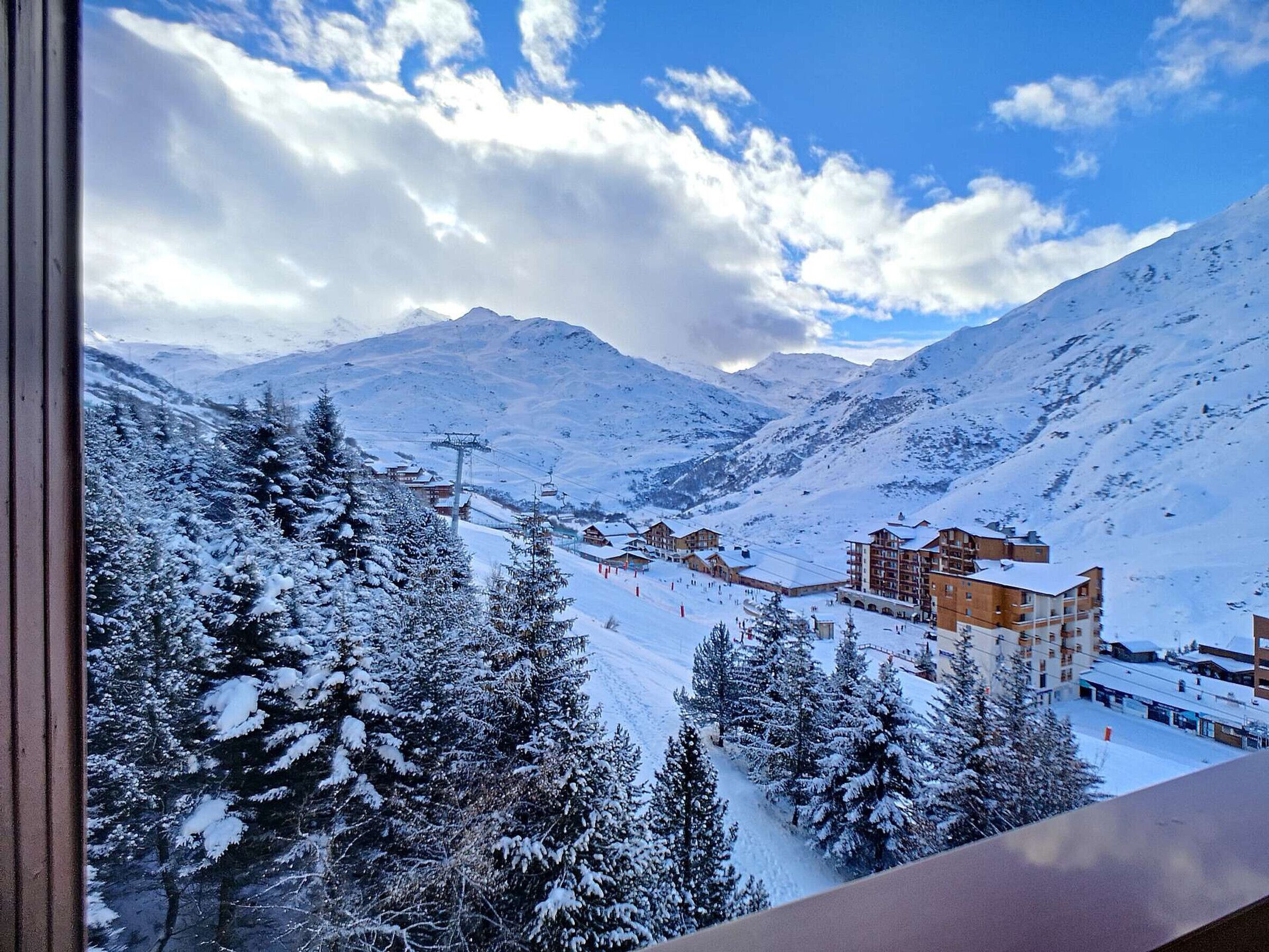 Ett snötäckt berglandskap med en skidort, inklusive byggnader och skidliftar.