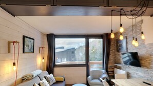 Un salon confortable avec un canapé, des fauteuils, une petite table et un téléviseur.