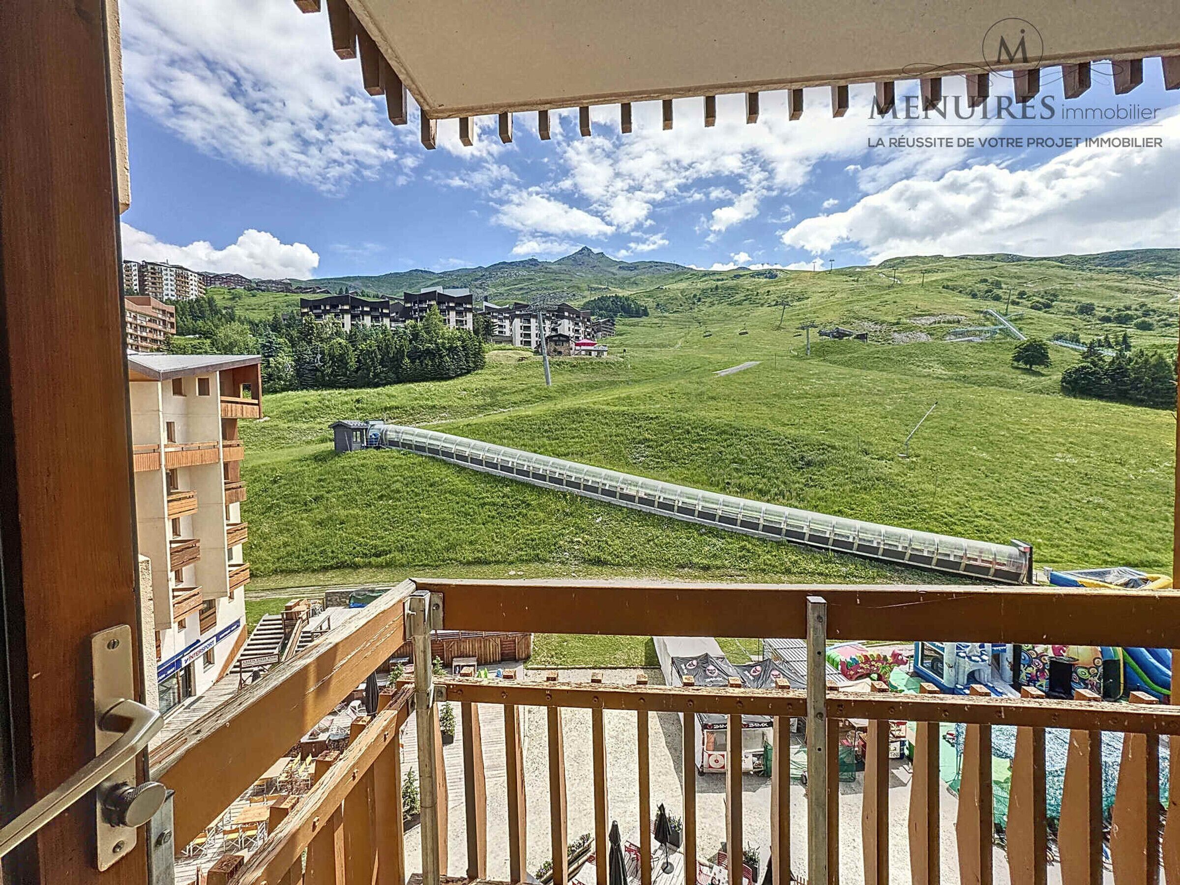 En balkong med utsikt över ett grönskande landskap, ett tåg och byggnader i bakgrunden.