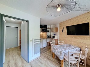 Um espaço compacto com área de refeições, cozinha compacta e TV fixada na parede.