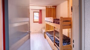 Ein Schlafsaalzimmer mit Etagenbetten, einem Fenster mit Vorhängen und einer Tür.