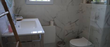A bathroom with a white sink, a toilet, and a shower area.