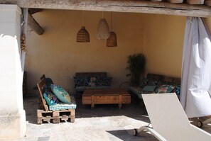 Un espace extérieur accueillant avec un banc en bois, un canapé confortable et une petite table.