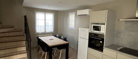 A kitchen with a dining table, chairs, a refrigerator, an oven, and a microwave.