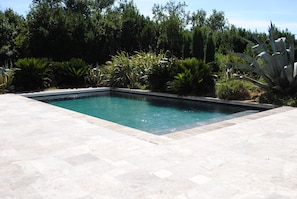 A rectangular swimming pool with a tiled deck surrounding it.