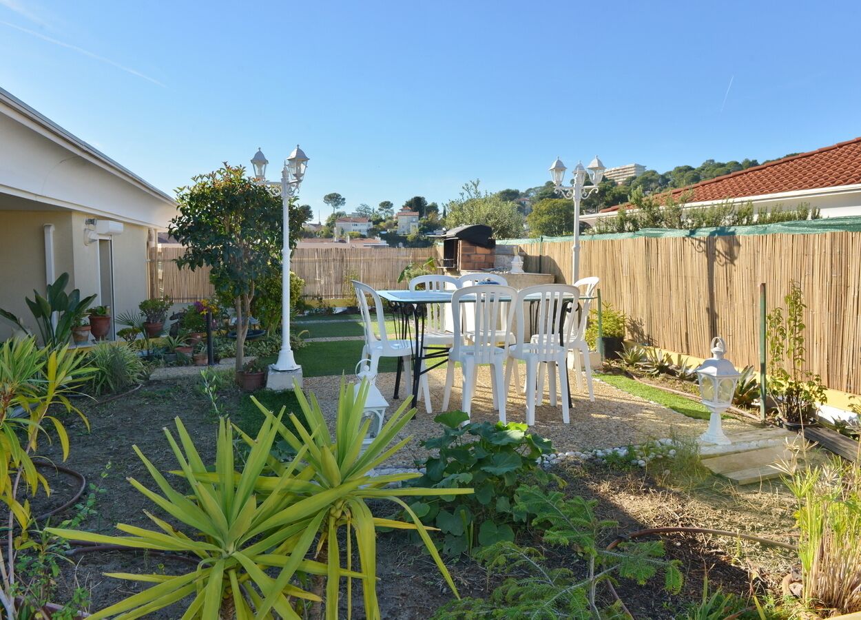 A backyard with a patio area, outdoor furniture, and various plants.