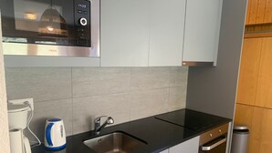 A modern kitchen with a black countertop, stainless steel sink, and a kettle.
