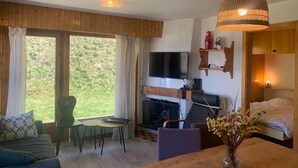 A cozy living room with a fireplace, a television, a dining table, and a sofa.