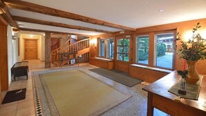 A spacious room with a wooden staircase, large windows, and a wooden bench.
