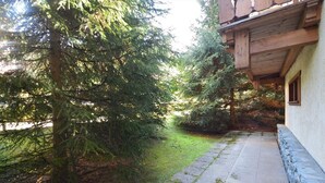 A stone pathway leading to a wooden building with a balcony, surrounded by dense evergreen trees.