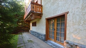 A building with a stone foundation, a wooden balcony, and a large window with a grid pattern.