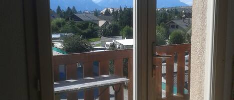 A room with a large window overlooking a street and mountains.