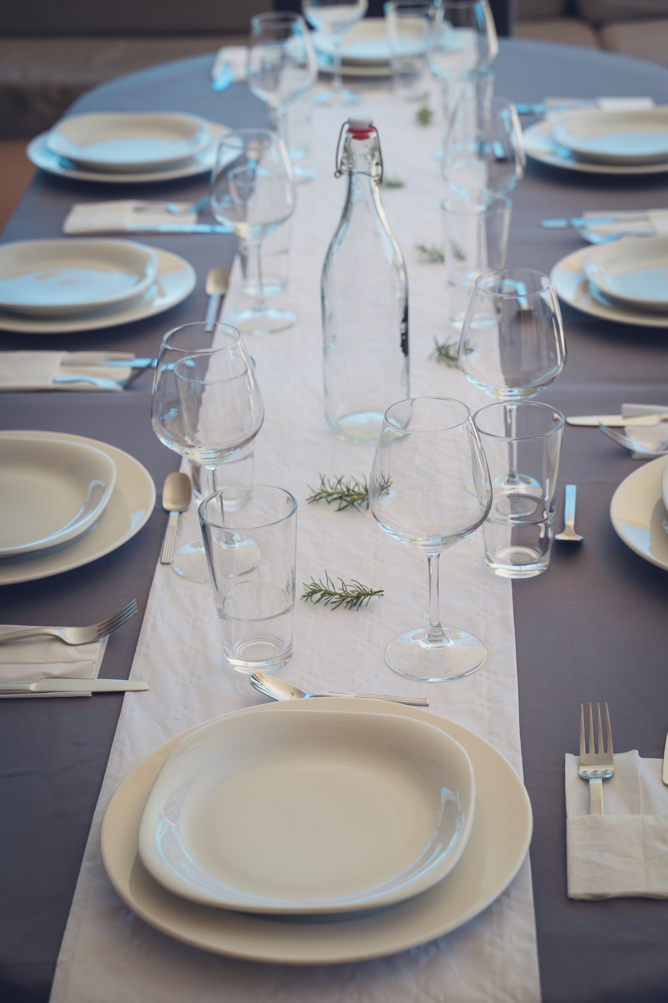 A table set for a meal with plates, glasses, and a bottle.