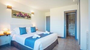 Een hotelkamer met een groot bed, een kunstwerk aan de muur en een deur naar een badkamer.