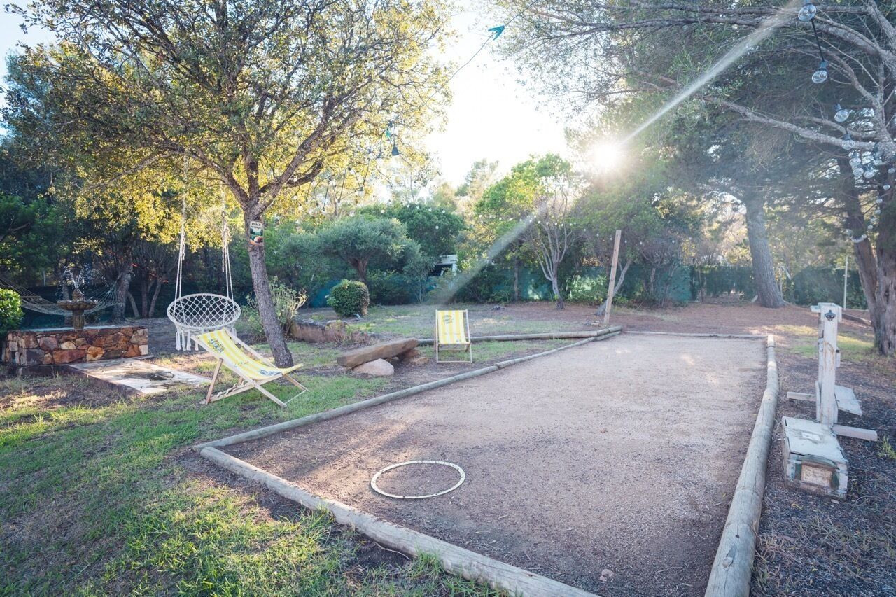 A garden with a ping pong table, a hammock, and a swing set.