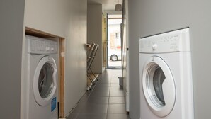 A laundry room with two washing machines, a striped rug, and a door leading to another room. - Holiday house 6 pers. in Etel, beach at 100 m (Étel)