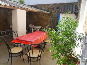 An outdoor patio with a table and chairs, a potted plant, and a stone wall. - Holiday house 6 pers. in Etel, beach at 100 m (Étel)