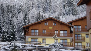 Un chalet en bois doté de balcons, entouré d’arbres couverts de neige.