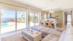 A spacious living room with a large sofa, a coffee table, and a view of a pool and outdoor area. - Altea HILLS, Luxury Villa, Wonderful View! (Altea)