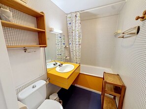 Une salle de bain avec un lavabo jaune, des toilettes blanches et une baignoire.